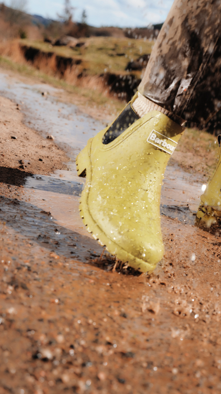 Rainwear collection banner featuring the Barbour wellingtons and rain mac, splashing around in a muddy scene Rainwear collection banner featuring the Barbour wellingtons and rain mac, splashing around in a muddy scene