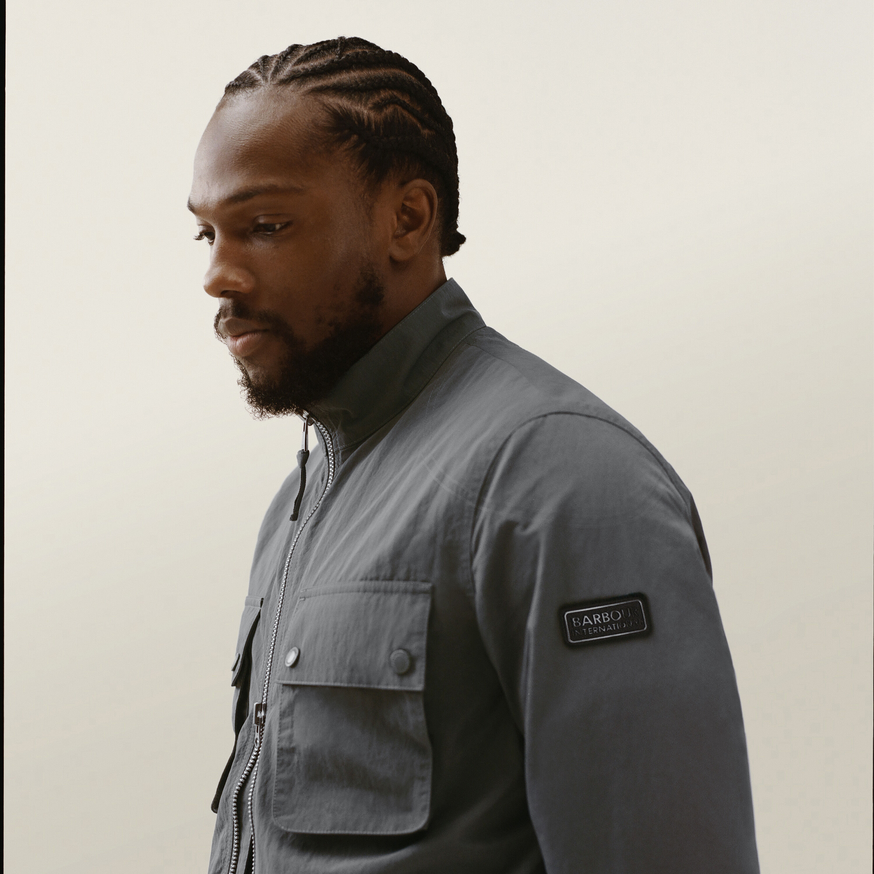 Tosin Cole wearing the Barbour International Course Showerproof Jacket in Washed Charcoal